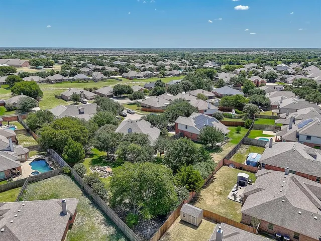 an aerial view of a residential houses with outdoor space and trees