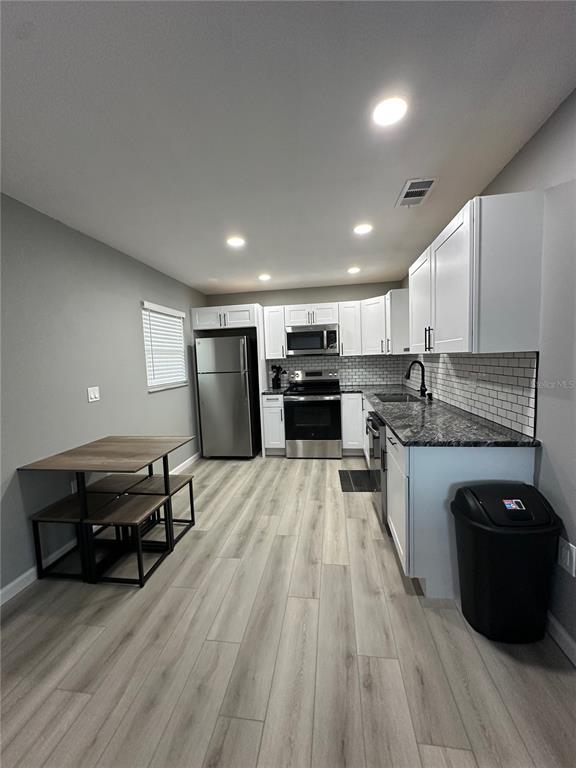 460 Base Avenue East, Unit 129 Venice, FL 34285 - Photo 2 of 33 a kitchen with stainless steel appliances granite countertop a refrigerator a stove a sink dishwasher and a stove with wooden floor