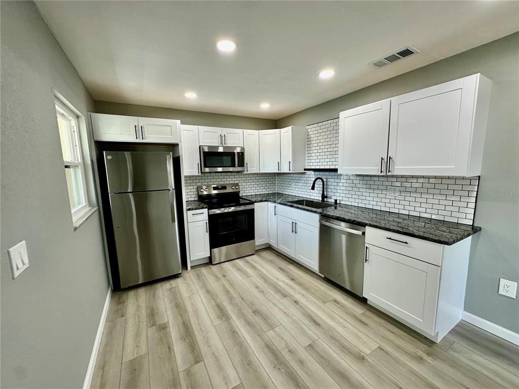 460 Base Avenue East, Unit 129 Venice, FL 34285 - Photo 3 of 33 a kitchen with stainless steel appliances granite countertop a refrigerator sink and cabinets