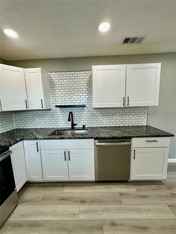 460 Base Avenue East, Unit 129 Venice, FL 34285 - Photo 6 of 33 a kitchen with granite countertop white cabinets sink and window