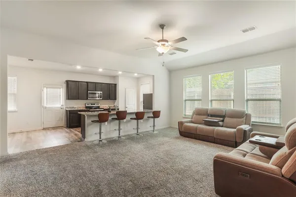 a kitchen with stainless steel appliances granite countertop a stove a sink a microwave a refrigerator and white cabinets