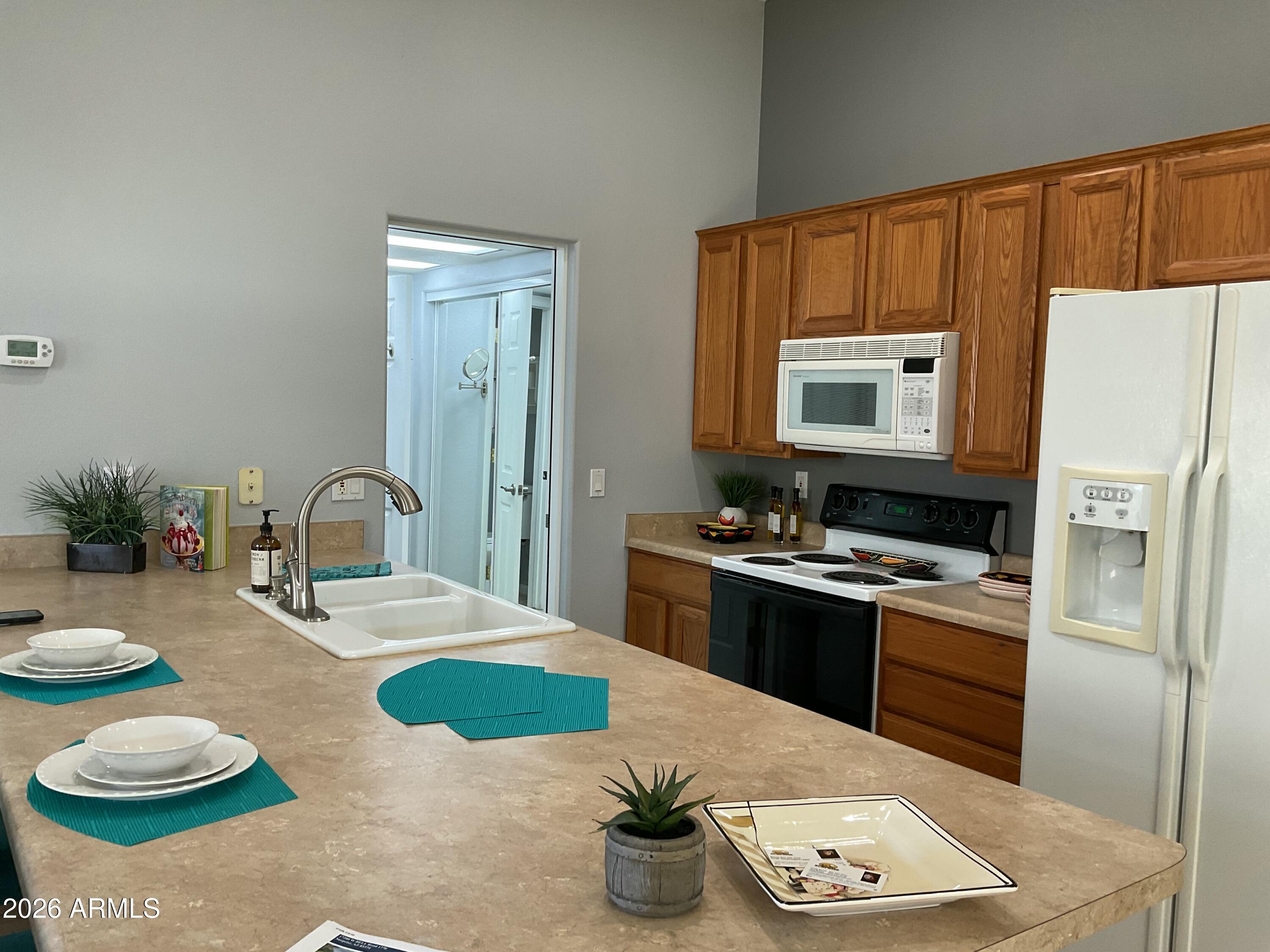 17200 West Bell Road, Unit 1770 Surprise, AZ 85374 - Photo 12 of 36 a kitchen with stainless steel appliances kitchen island granite countertop a refrigerator a stove and a sink