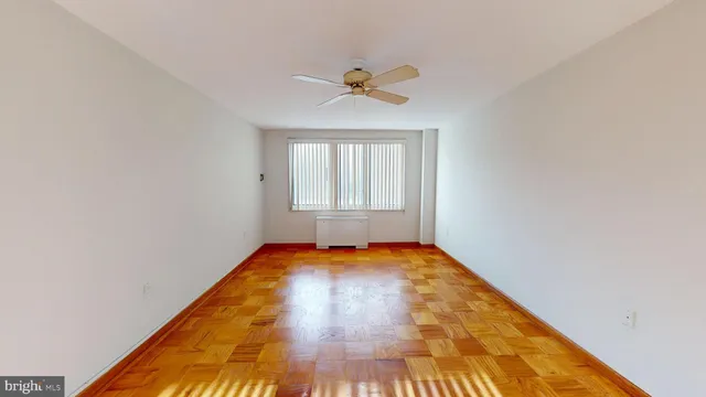 a view of empty room with wooden floor and fan