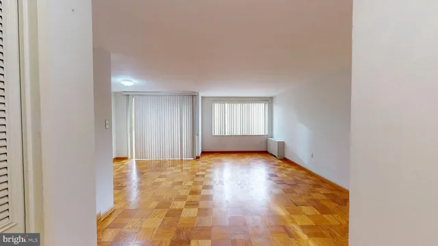 a view of an empty room with window and wooden floor