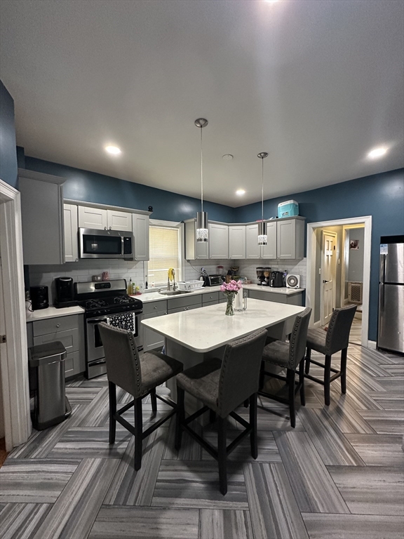 115 Addison Street Chelsea, MA 02150 - Photo 4 of 16 a kitchen with a dining table chairs and refrigerator