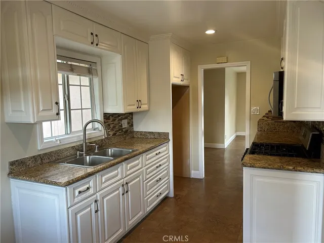 a kitchen with granite countertop a sink and a refrigerator