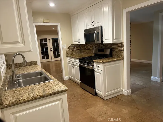 a kitchen with granite countertop a sink and stainless steel appliances
