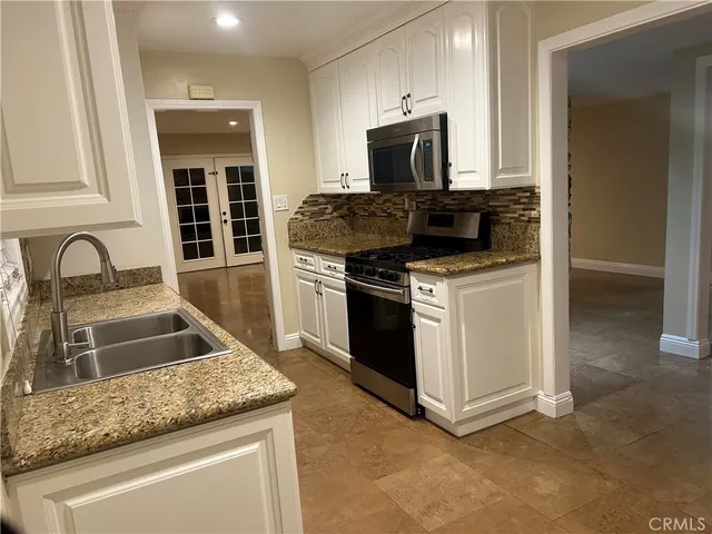 a kitchen with granite countertop a sink and stainless steel appliances