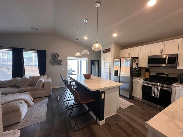a kitchen with stainless steel appliances granite countertop a kitchen island hardwood floor sink stove dining table and chairs