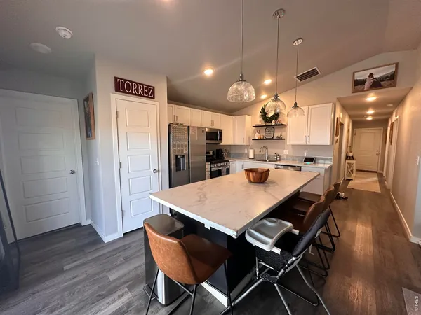 a kitchen with stainless steel appliances a refrigerator a stove a sink dishwasher and white cabinets with wooden floor