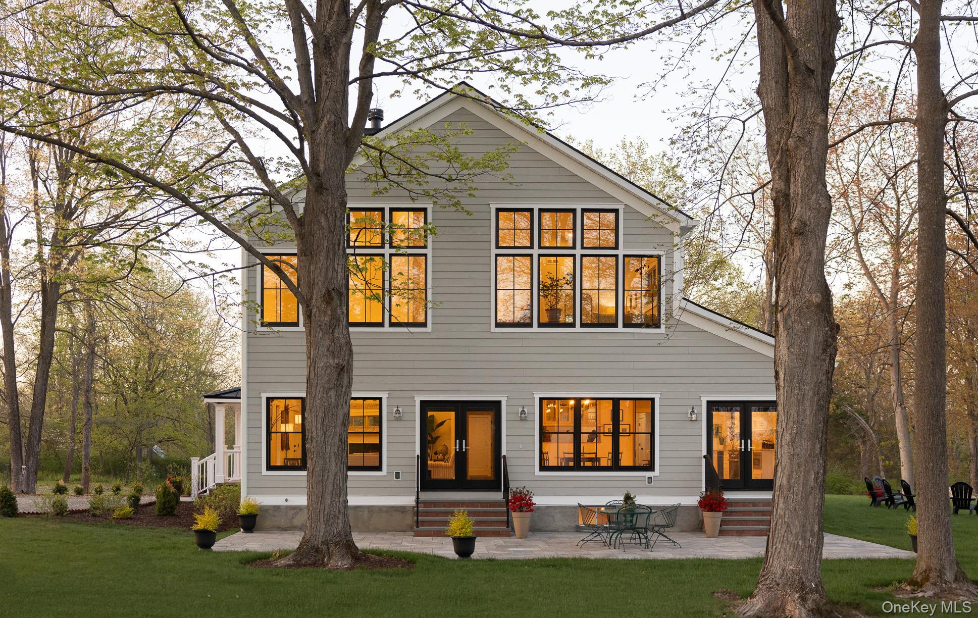 Southern side of the home with patio, two sets of patio doors, and extensive windows