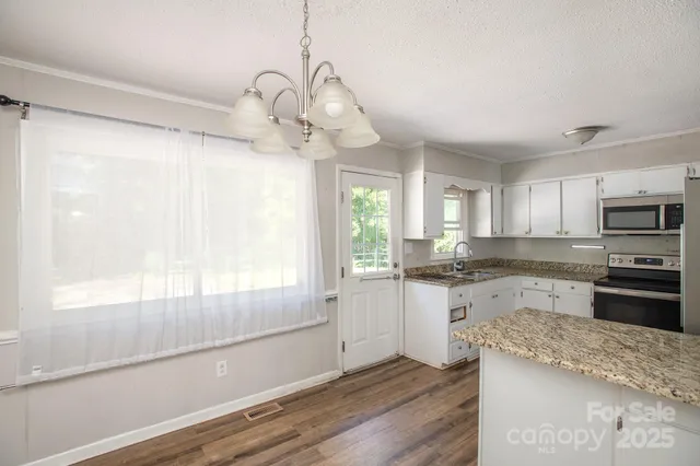 a kitchen with stainless steel appliances granite countertop a refrigerator stove and white cabinets