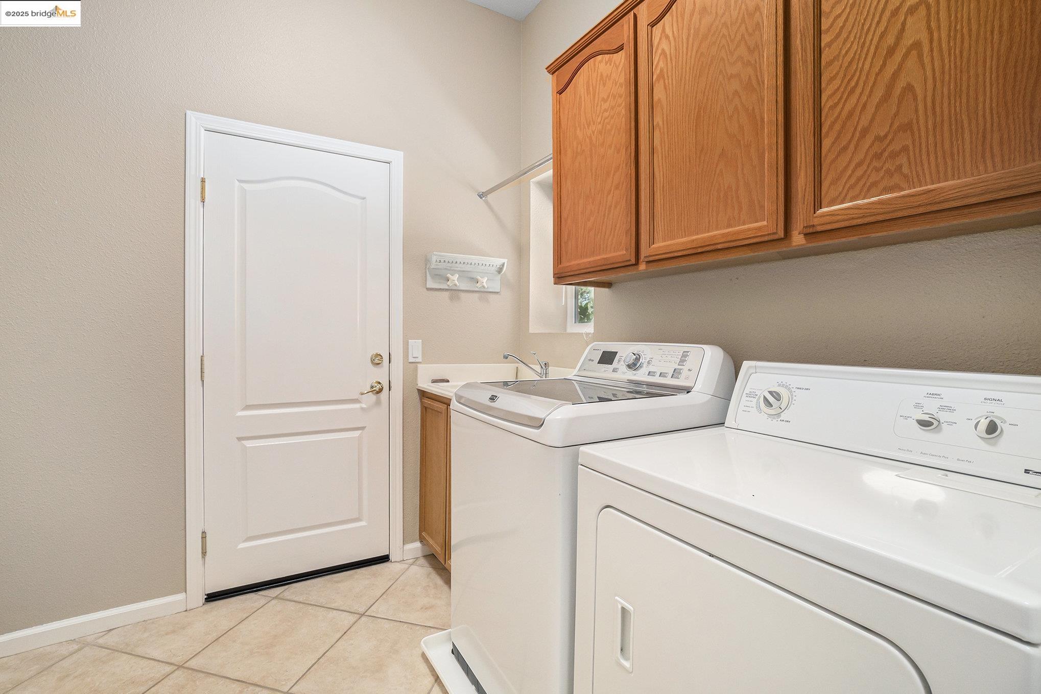 599 Pomona Drive Brentwood, CA 94513 - Photo 18 of 35 Laundry room featuring washer and clothes dryer, cabinet space, and light tile patterned floors
