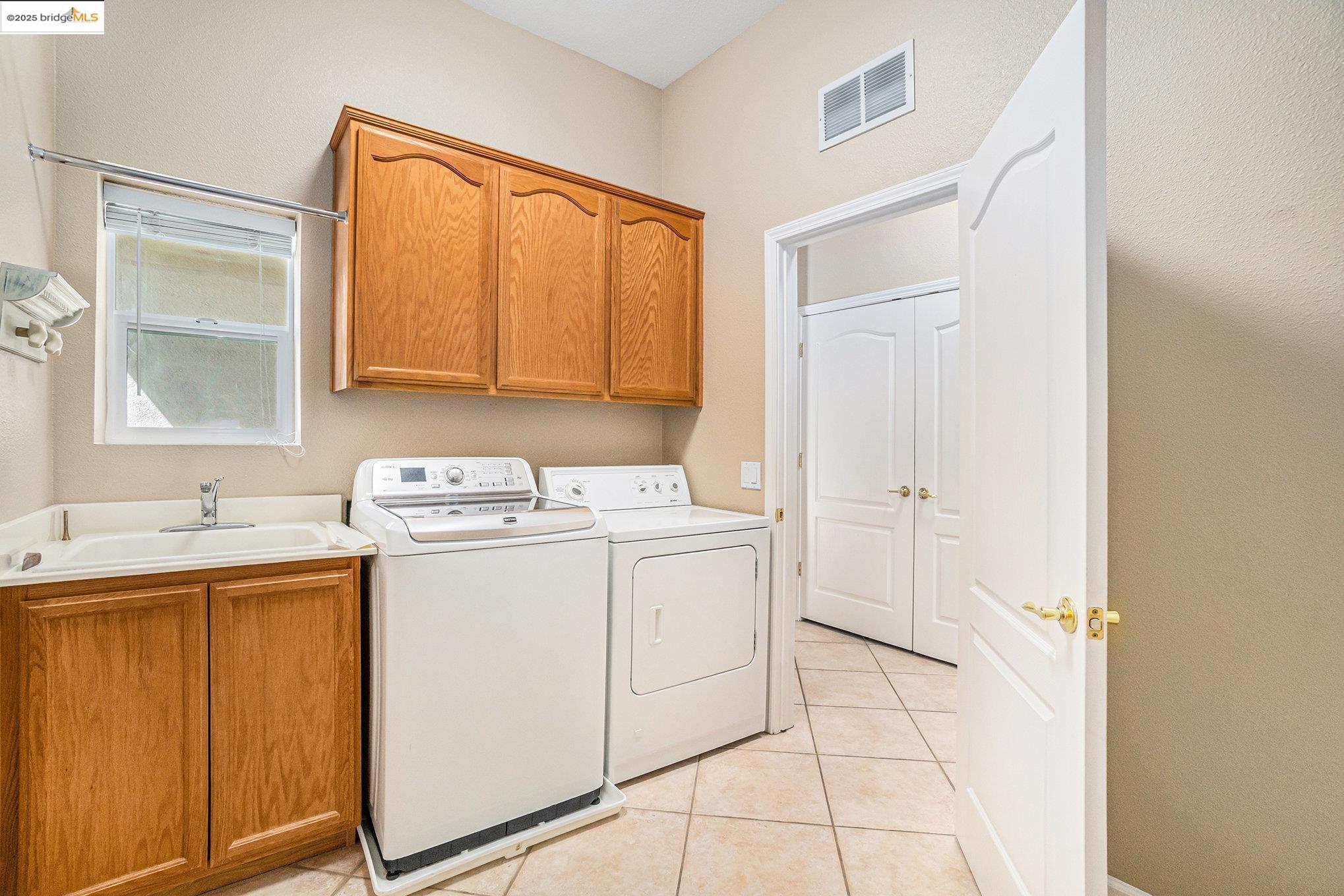 599 Pomona Drive Brentwood, CA 94513 - Photo 19 of 35 Laundry area featuring cabinet space, washing machine and clothes dryer, and light tile patterned floors