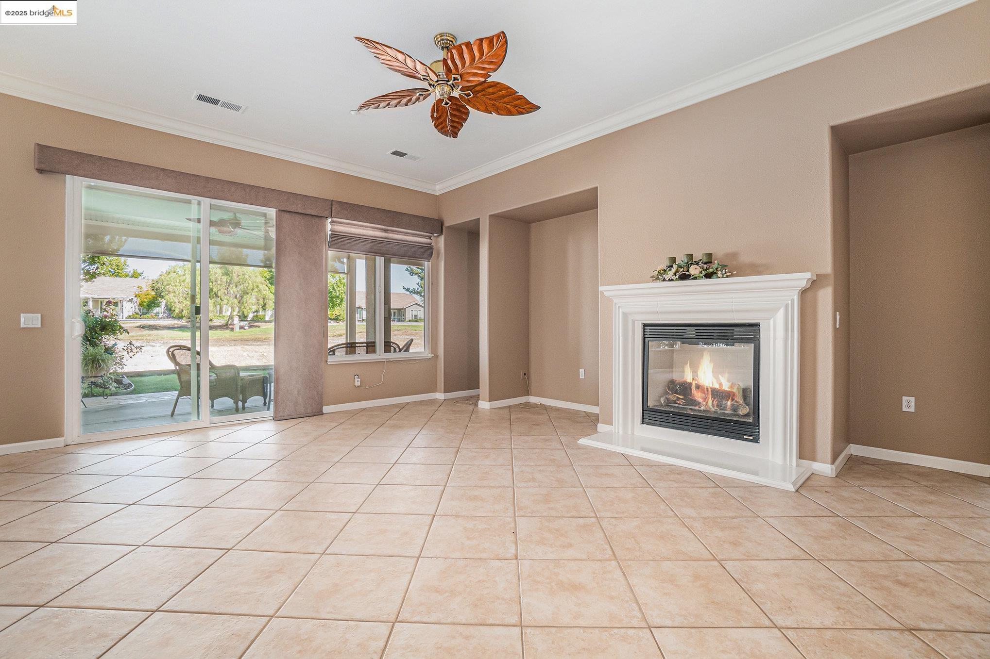 599 Pomona Drive Brentwood, CA 94513 - Photo 2 of 35 Unfurnished living room featuring crown molding, light tile patterned floors, a glass covered fireplace, and ceiling fan