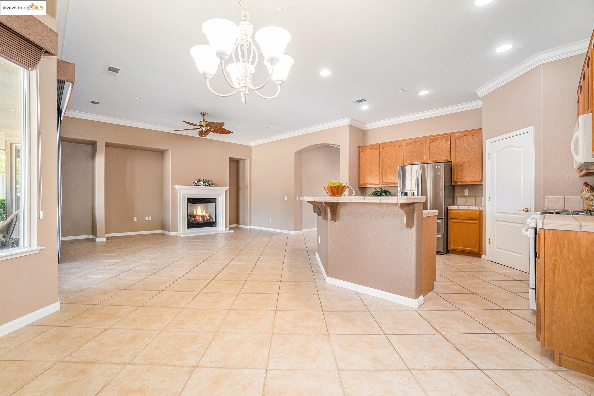 599 Pomona Drive Brentwood, CA 94513 - Photo 4 of 35 Kitchen featuring a glass covered fireplace, light tile patterned flooring, a breakfast bar area, ornamental molding, and ceiling fan