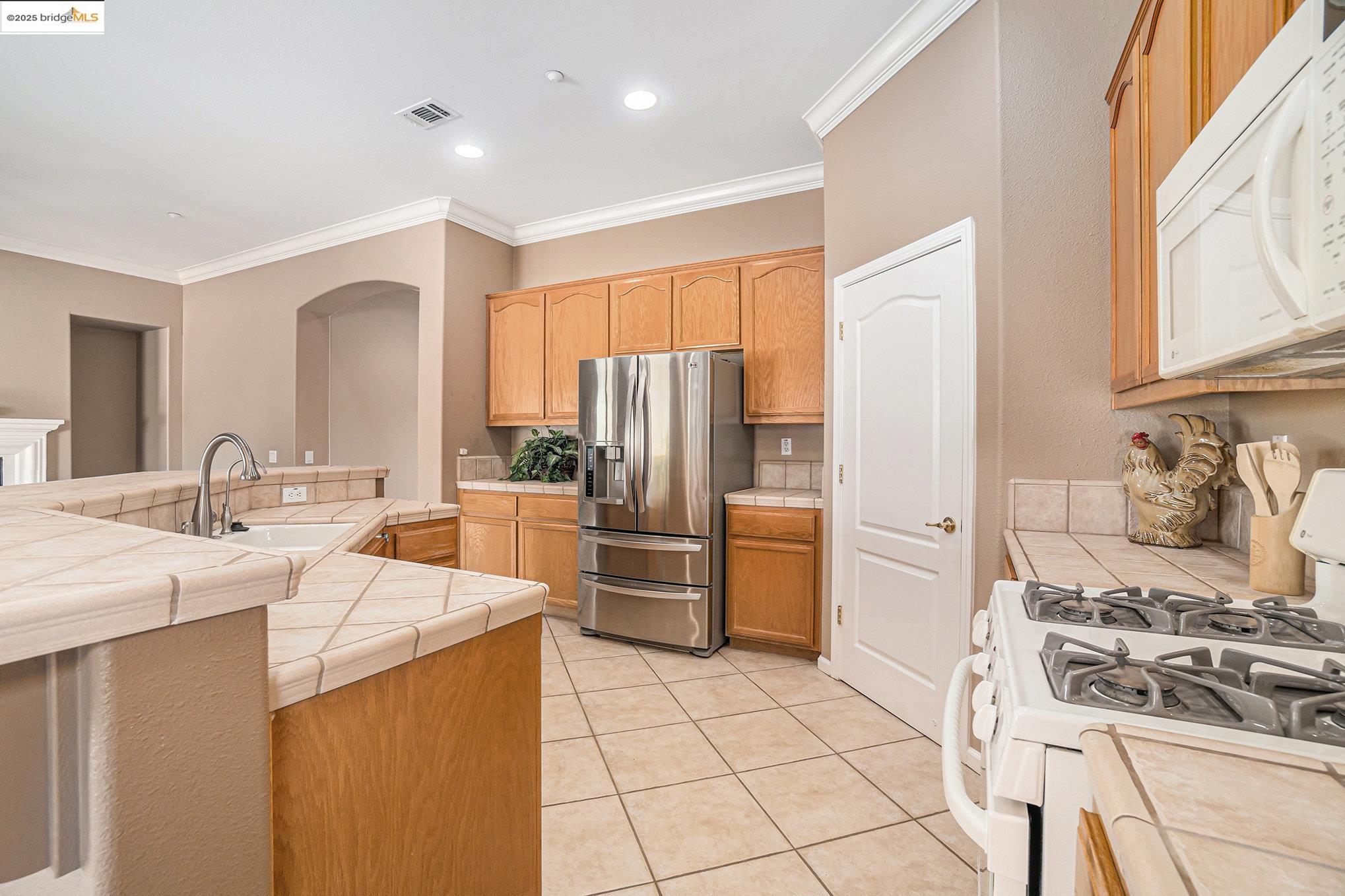 599 Pomona Drive Brentwood, CA 94513 - Photo 5 of 35 Kitchen with white appliances, ornamental molding, tile counters, light tile patterned flooring, and recessed lighting