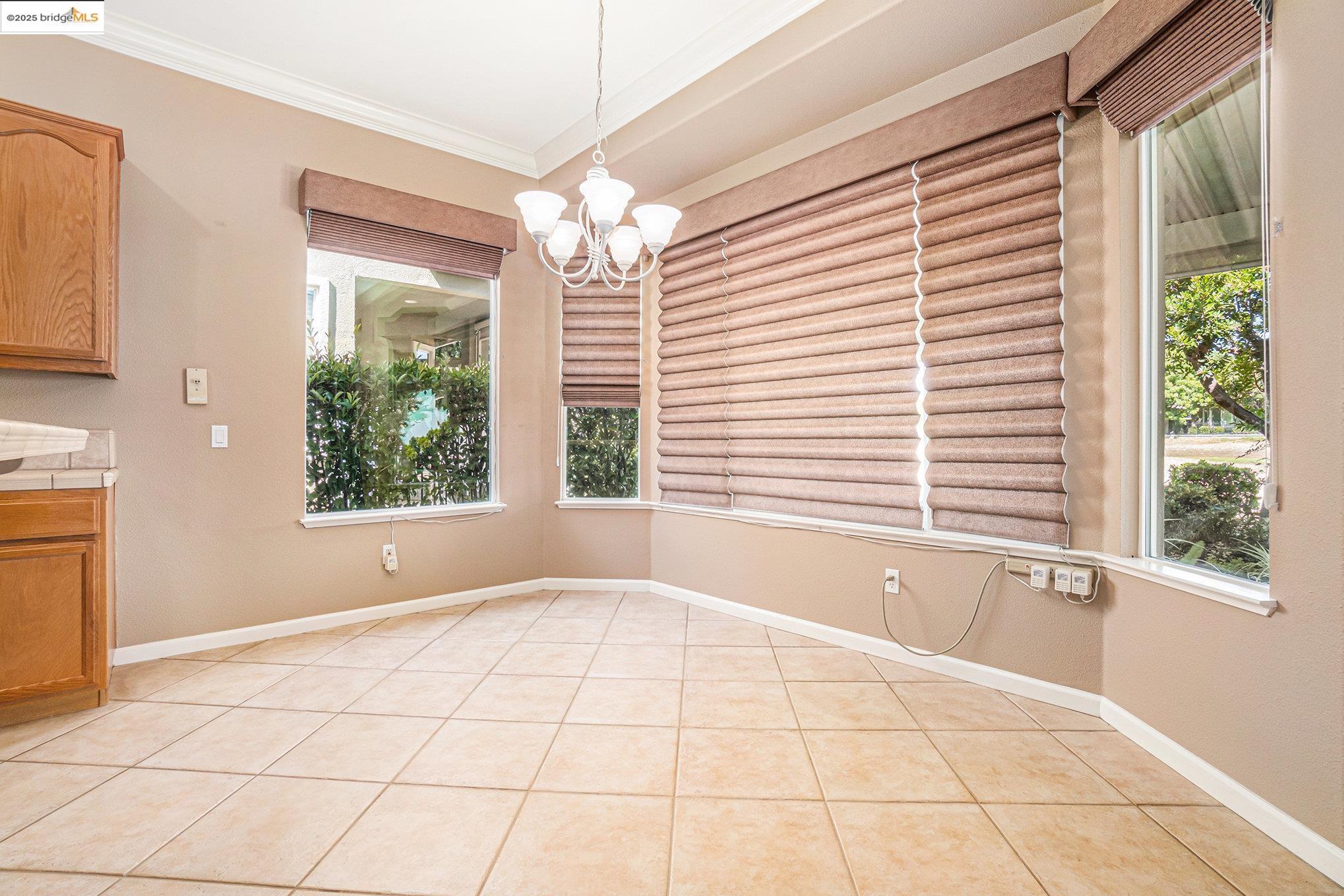599 Pomona Drive Brentwood, CA 94513 - Photo 8 of 35 Unfurnished dining area featuring crown molding, a chandelier, light tile patterned floors, and plenty of natural light
