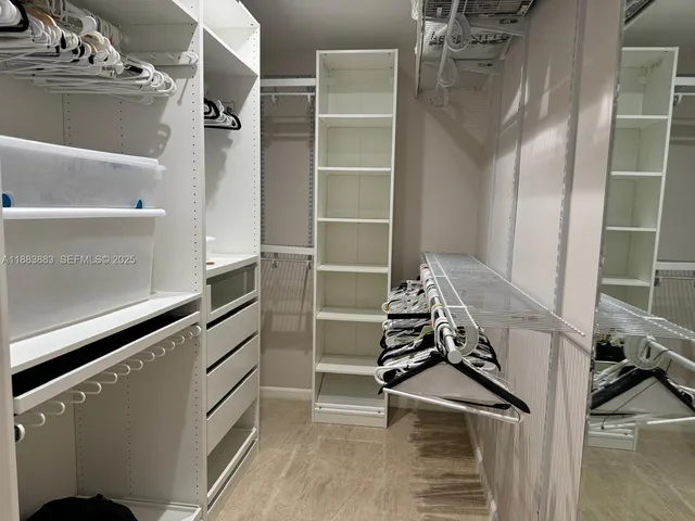 a view of walk in closet with clothes and shoes