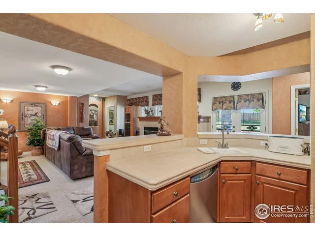 a kitchen with a sink a counter top space and living room view
