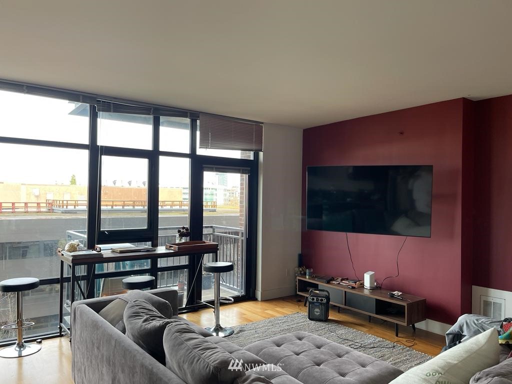 2911 2nd Avenue, Unit 818 Seattle, WA 98121 - Photo 5 of 16 a living room with furniture a flat screen tv and floor to ceiling window