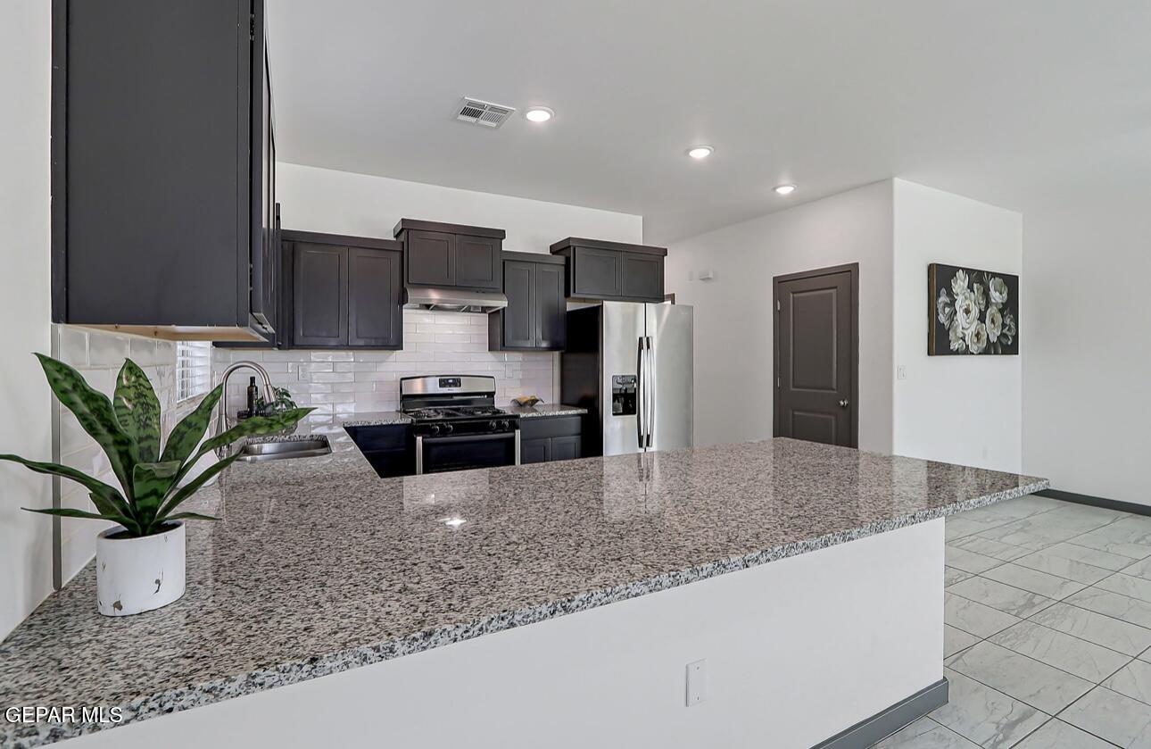 4572 Mark Avizo El Paso, TX 79938 - Photo 5 of 32 a kitchen with stainless steel appliances granite counter a refrigerator a sink a stove a washer dryer