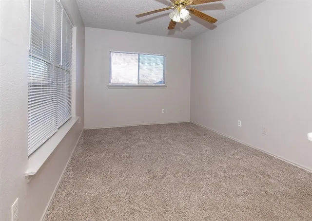 an empty room with a chandelier fan and windows