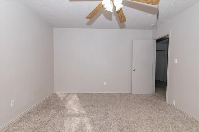an empty room with windows and fan chandelier fan