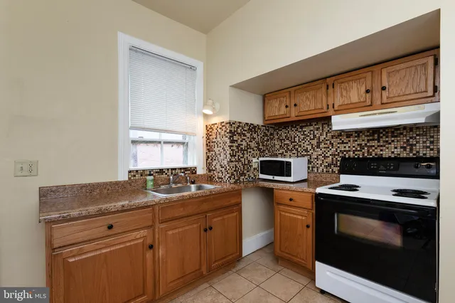 a kitchen with granite countertop a stove sink and cabinets
