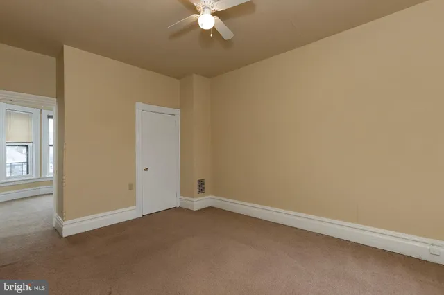 an empty room with a fan & a window