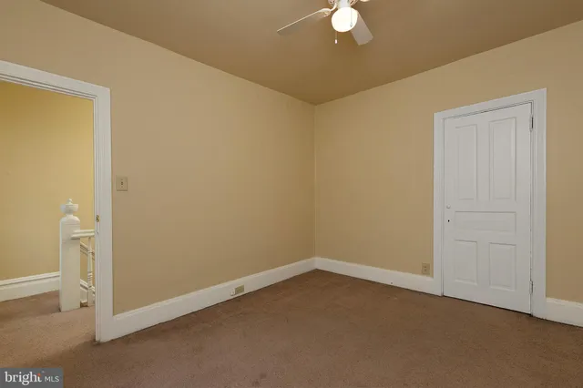 an empty room with a fan & a window