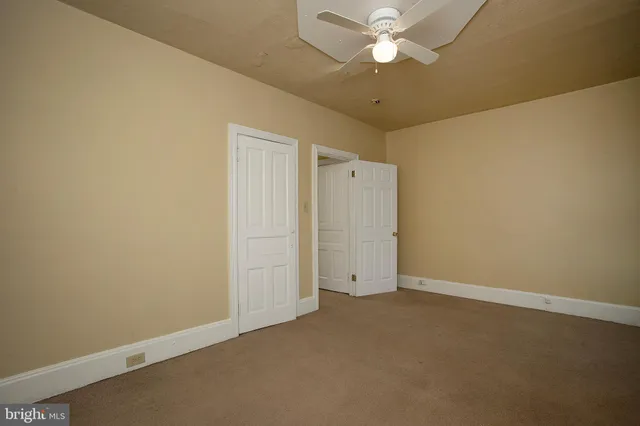 an empty room with closet and a chandelier fan