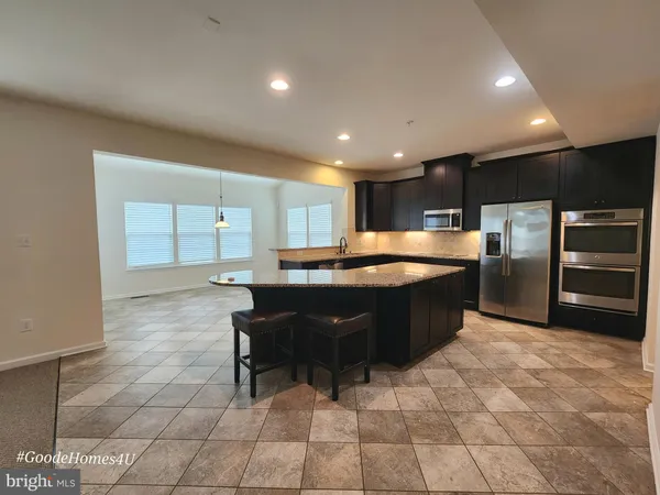 a large kitchen with kitchen island granite countertop a sink counter and chairs