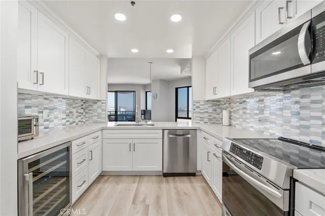 a kitchen with stainless steel appliances granite countertop hardwood floor sink stove and white cabinets