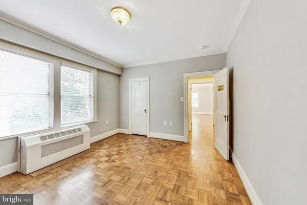 a view of an empty room with window and cabinet area