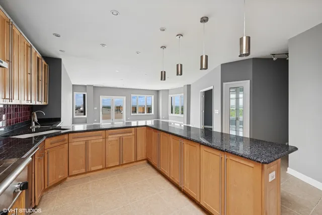 a large white kitchen with granite countertop a sink and dishwasher a stove top oven with wooden floor
