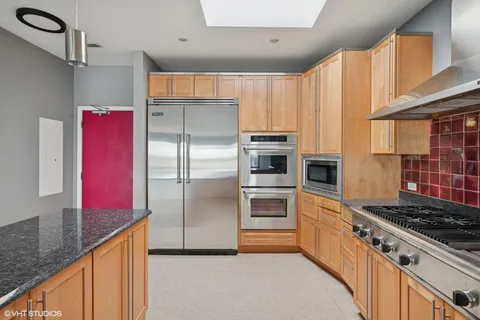 a kitchen with stainless steel appliances kitchen island granite countertop a refrigerator and a stove top oven