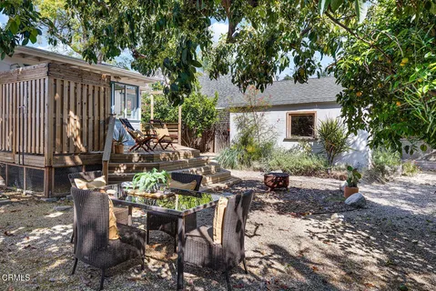 a view of a patio with table and chairs potted plants and large tree