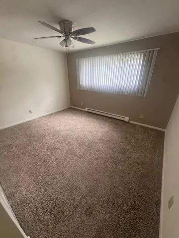 an empty room with windows and fan