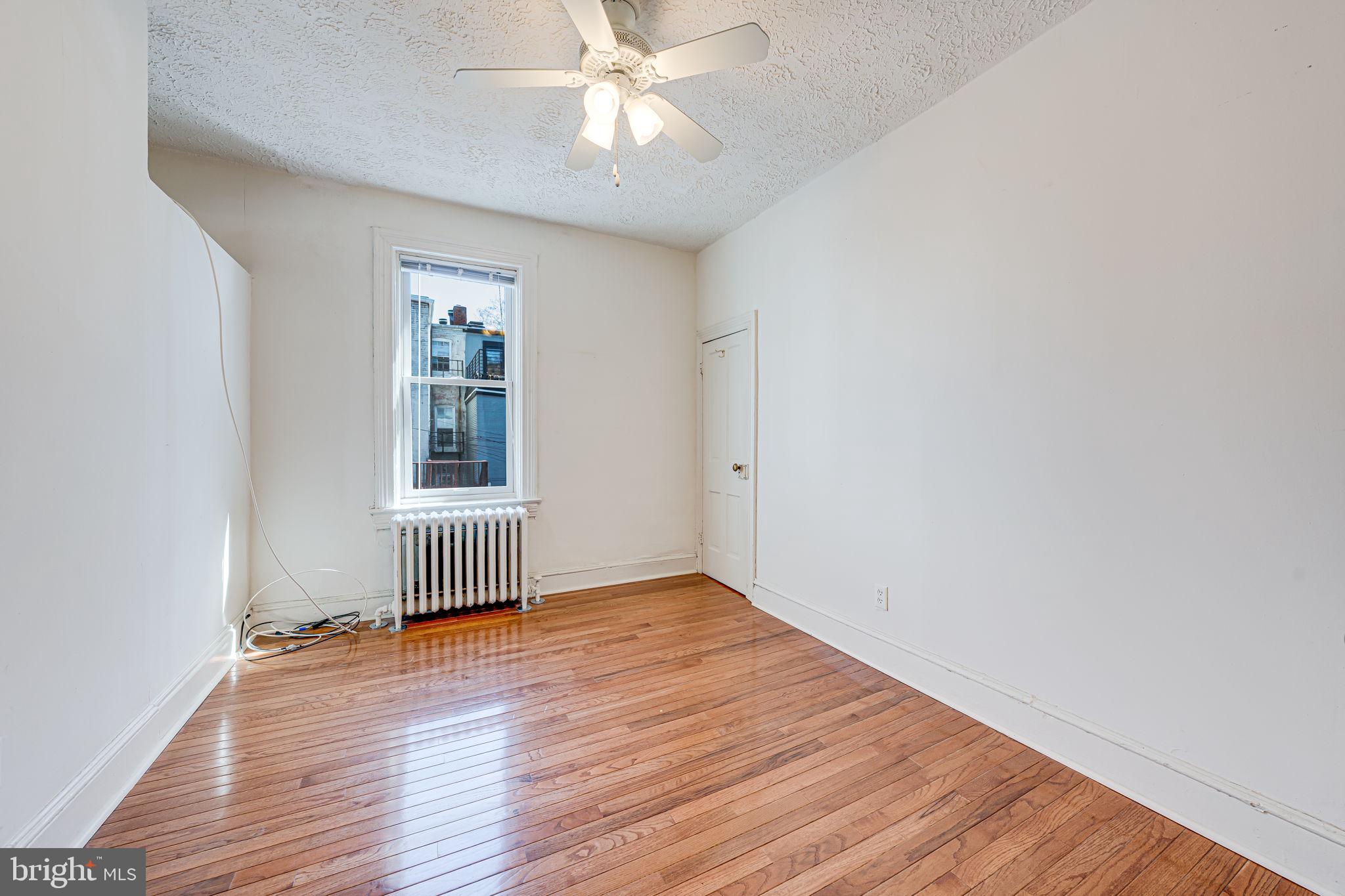 1502 Caroline Street Northwest Washington, DC 20009 - Photo 15 of 22 an empty room with wooden floor chandelier fan and windows