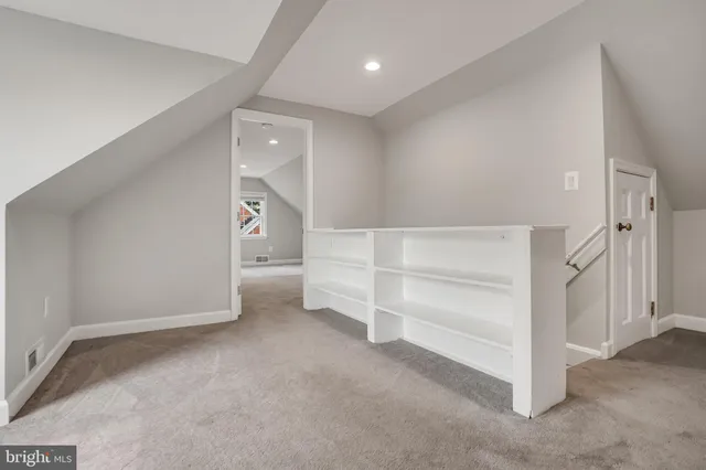 a view of an empty room with a cabinet and mirrors
