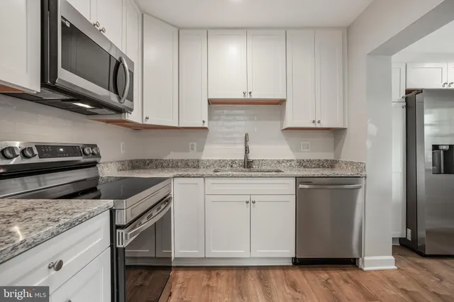 a kitchen with stainless steel appliances granite countertop a stove a sink and a microwave