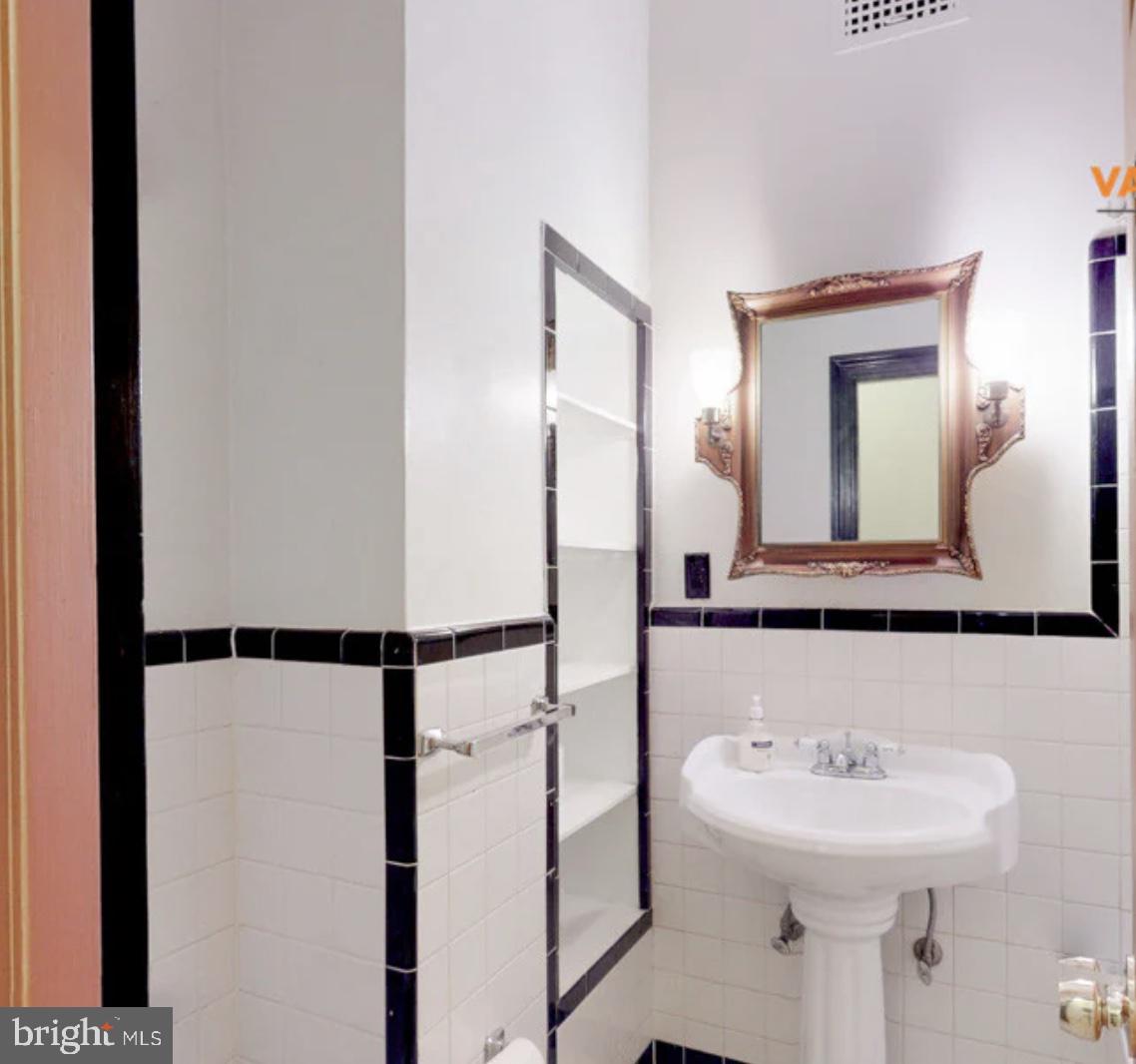 1 East Chase Street, Unit 804 Baltimore, MD 21202 - Photo 7 of 31 a bathroom with a sink a mirror and shower