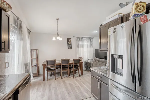 a kitchen with stainless steel appliances kitchen island granite countertop dining table chairs and a refrigerator