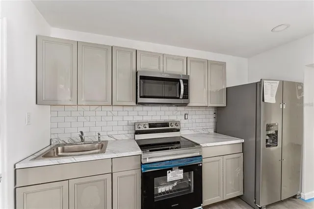 a kitchen with stainless steel appliances granite countertop white cabinets and a stove top oven