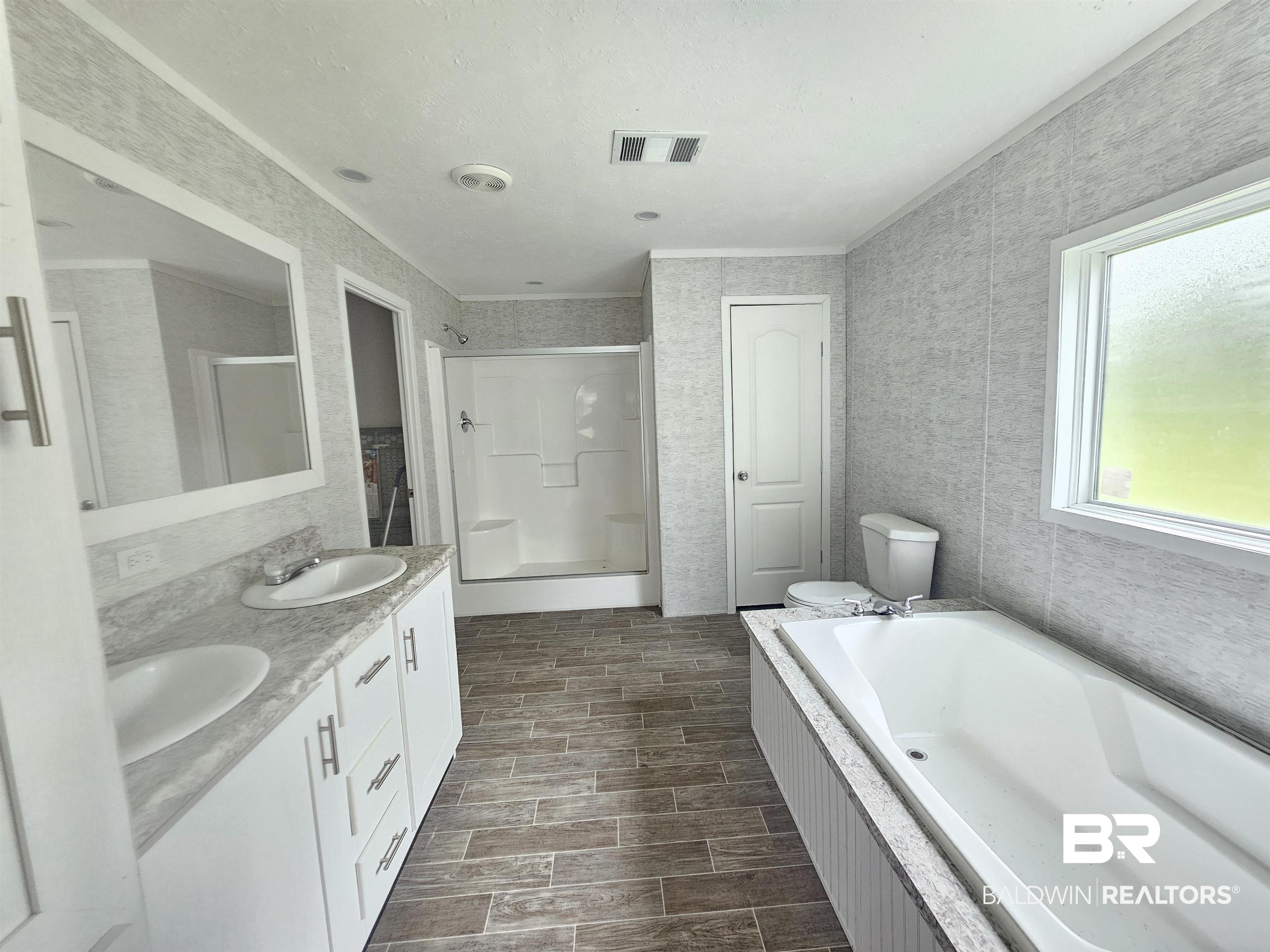 1863 Wait Road Monroeville, AL 36460 - Photo 9 of 38 Full bathroom with independent shower and bath, toilet, double sink vanity, and tile walls