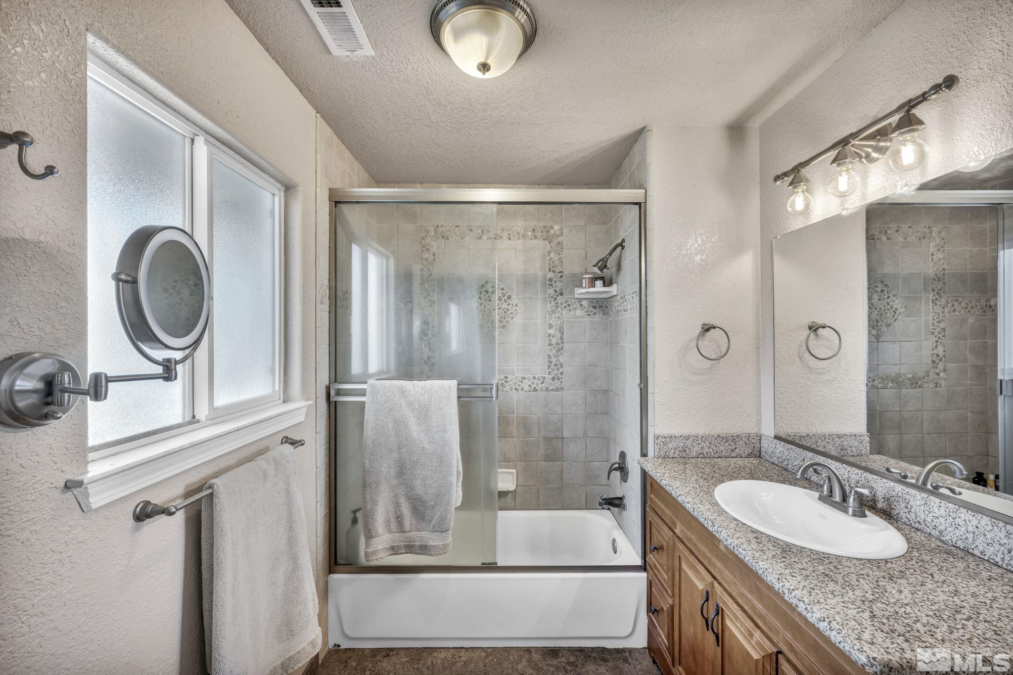 14660 Chamy Drive Reno, NV 89521 - Photo 25 of 38 a bathroom with a granite countertop sink a mirror and a shower