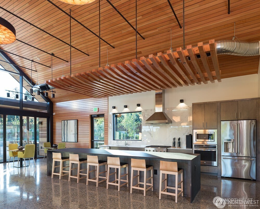 3311 Colville Street Southeast Lacey, WA 98513 - Photo 37 of 40 a kitchen with stainless steel appliances granite countertop a stove a refrigerator a dining table and chairs with wooden floor