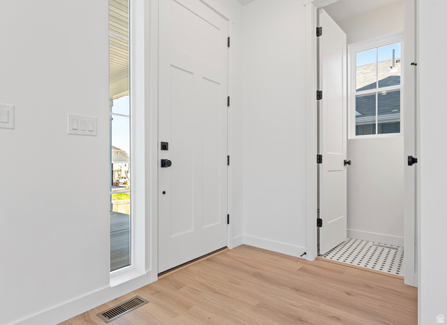 11214 South Easy Bee Road, Unit 270 South Jordan, UT 84009 - Photo 3 of 31 Entryway featuring a solid panel door with black hardware, wood-finish flooring, a sidelight window, and a utility space with a window and mosaic tile flooring