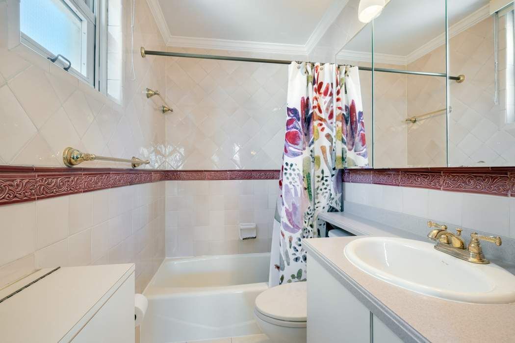 501 East 79th Street, Unit 14E Manhattan, NY 10075 - Photo 10 of 19 a bathroom with a sink a toilet and shower curtain